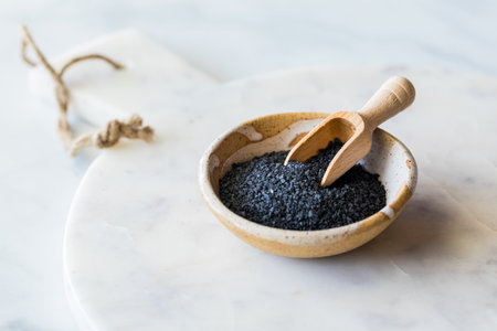 Black Hawaiian salt in a bowl with a small wooden scoop.の写真素材