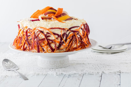 A colourful carrot cake garnished with rainbow carrot shavings.の写真素材