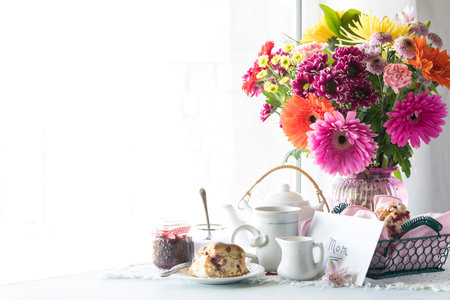A beautiful Mothers Day arrangement with tea, scones and a bouquet of flowers.の写真素材