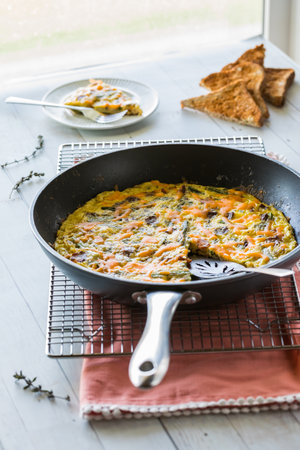 A frying pan holding a bacon and asparagus frittata ready for serving.の写真素材