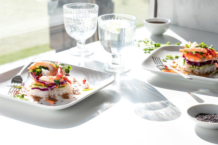 Asian Salad roll stacks on a table in bright sunlight with sparkling water.の写真素材