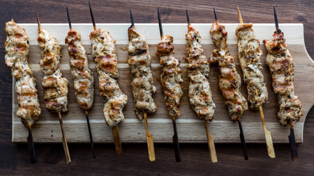 Top down view of a wooden board topped with grilled chicken skewers.