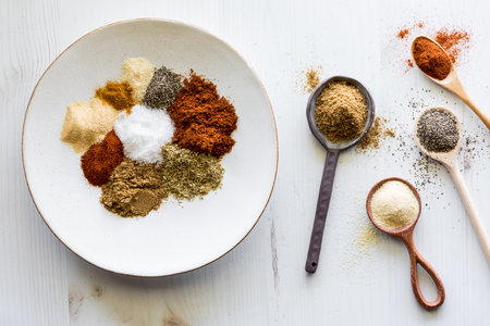 Various spoons with messy piles of spices used to make a taco seasoning blend.の写真素材