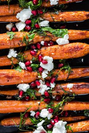 Honey roasted carrots topped with goat cheese, herbs and pomegranate arils.の写真素材