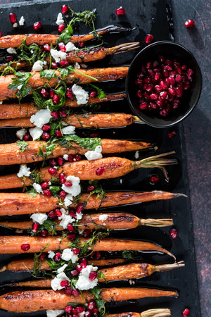 Roasted carrots topped with cheese, herbs and pomegranate arils.の写真素材
