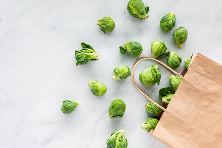 Brussel sprouts pouring out of a paper bag onto a marble surface.の写真素材
