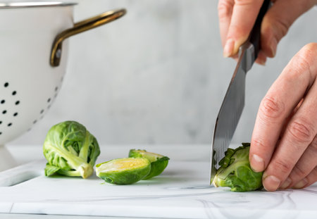 A close up of hands preparing fresh brussel sprouts for cooking.の写真素材