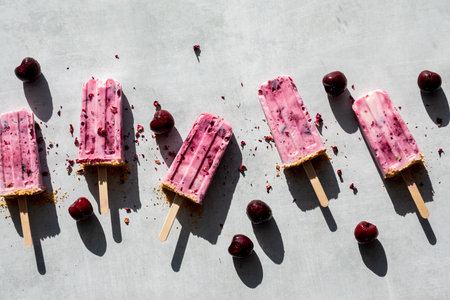 A row of cherry yogurt pops in bright sunlight with dark shadows cast below.の写真素材