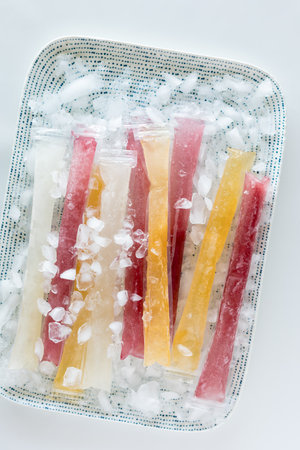 Homemade fruit flavoured freezies on a tray of ice.の写真素材