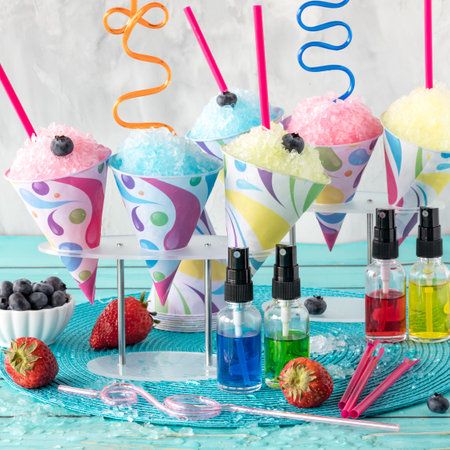 Fruit flavoured icy snow cones with different flavour syrups in front.の写真素材
