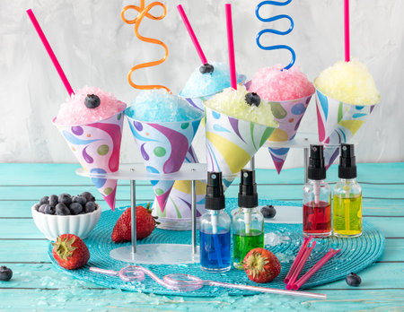 A variety of icy snow cones with fruit flavoured syrups in front.の写真素材
