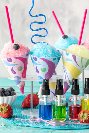 A vertical view of various snow cones with flavoured syrups in front.の写真素材