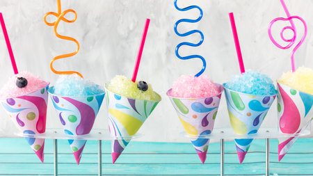 A row of colourful snow cones with crazy straws, ready for sharing.の写真素材