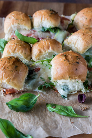 Pull apart Italian sub sliders topped with fresh basil leaves.の写真素材