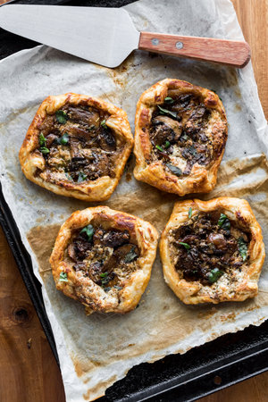 Savoury gourmet mushroom pastries on a parchment lined pan, hot out of the oven.の写真素材