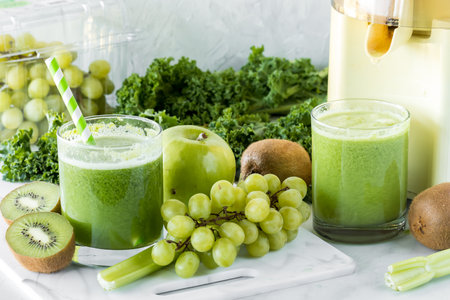 Glasses of freshly made green juice with ingredients all around.の写真素材