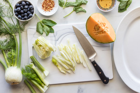Above view of ingredients for preparing a fennel, melon and blueberry salad.の写真素材