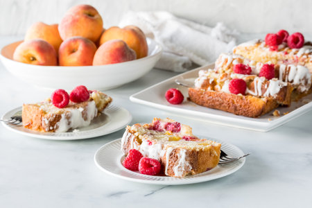 Servings of raspberry peach bread with the remaining loaf and peaches in behind.の写真素材