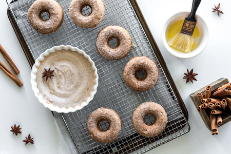 Homemade doughnuts on a cooling rack with cinnamon sugar and melted butter.の写真素材