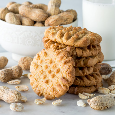 A close up of a stack of homemade peanut butter cookies with a bowl of peanuts.の写真素材