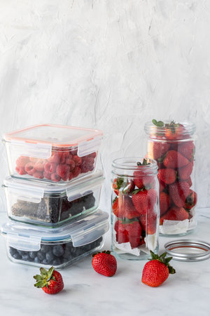 Glass containers storing various berries against a light background