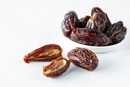 Cut and whole medjool dates against a white background.