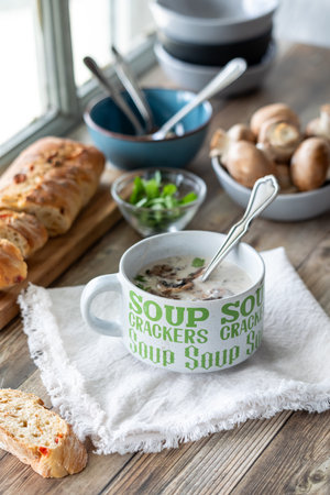 Above view of a cup of cream of mushroom soup served with a crusty baguette.の写真素材