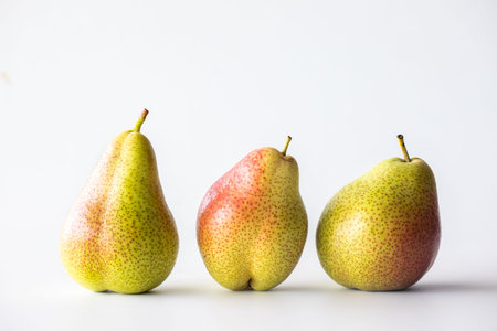 Whole Forelle pears standing in a row, against a light background.の写真素材