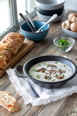 A bowl of cream of mushroom soup served with crusty bread, ready for eating.の写真素材