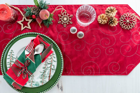 Assorted holiday ornaments on a table runner with festive dishes.