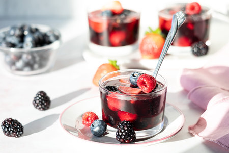 A homemade mixed berry gelatin cup topped with fresh berries, ready for eating.