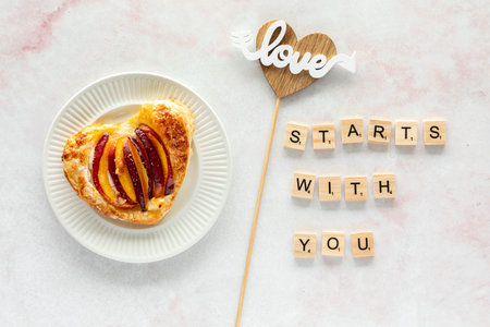 A self love concept background with a single heart shaped peach pastry tart.