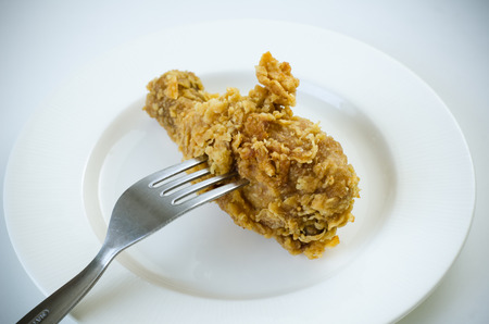 Fresh crispy fried chicken with stainless steel fork on white plateの写真素材