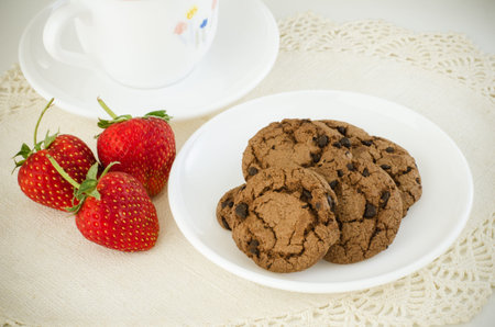 Chocolate cookie in white plate with fresh red strawberriesの写真素材
