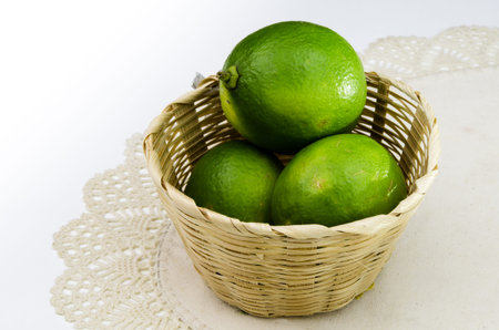 fresh lime in bamboo bucket on white fabricの写真素材