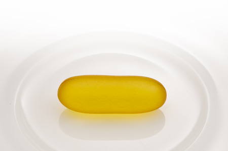 Fish oil, Yellow soft gel capsule in white ceramic dishの写真素材