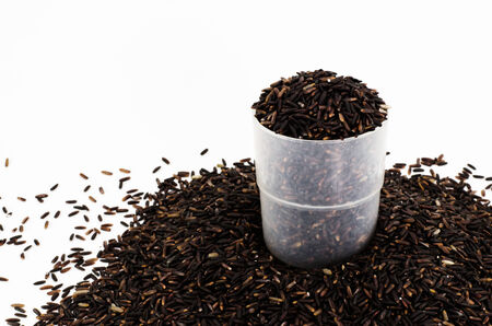 Organic black rice in plastic cup on white backgroundの写真素材