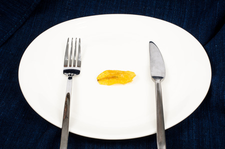 Image of dried banana snack in white plate with knife and forkの写真素材
