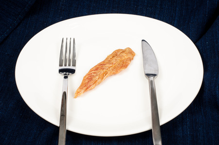 Image of dried chicken dog snack on white plate with knife and forkの写真素材