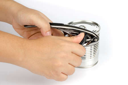 Woman's hand opening tin can with tin openerの写真素材