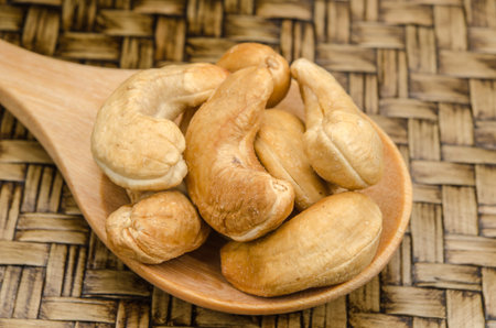 Image of cashew nuts in wooden spoon on bamboo tray