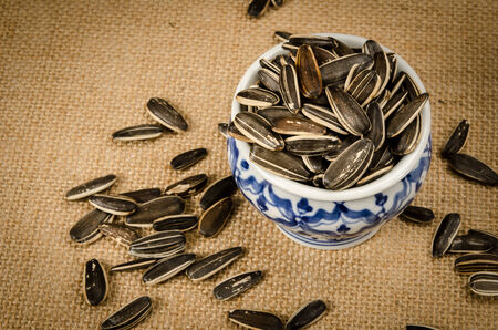 Image of sunflower seeds in ceramic bowl on brown sackの写真素材
