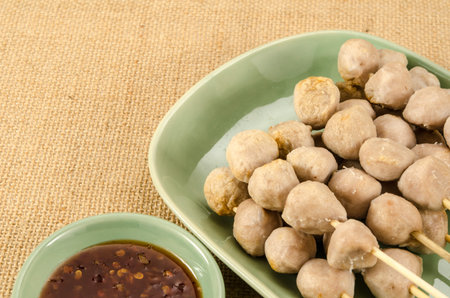 Meat ball with bamboo stick in green ceramic dish on brown sack backgroundの写真素材