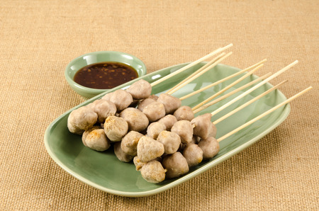 Meat ball with bamboo stick in green ceramic dish on brown sack backgroundの写真素材