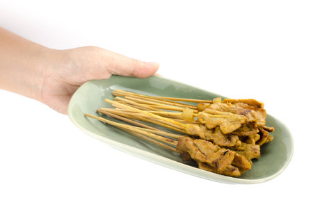 Grilled Pork Satay in green ceramic dish hold by handの写真素材