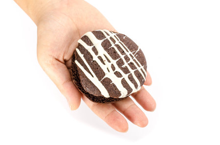 Image of chocolate cookie cake in human hand on white backgroundの写真素材