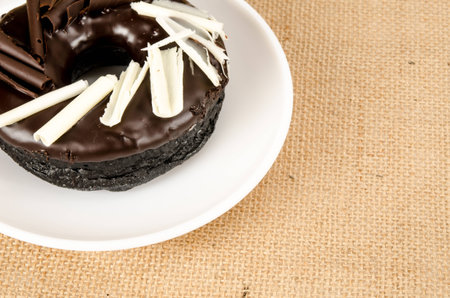 Chocolate donut in white dish on brown sack backgroundの写真素材