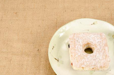 Image of square donut in ceramic dish on brown sack backgroundの写真素材