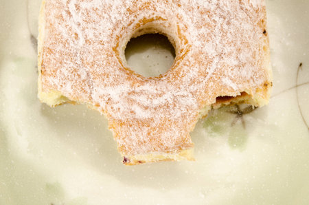 Image of square donut with bite taken out in ceramic dish on brown sack backgroundの写真素材