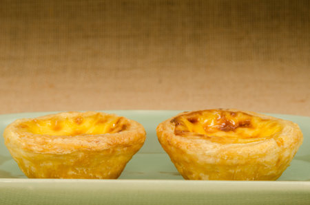 Image of egg tart in green ceramic dish on brown sack background